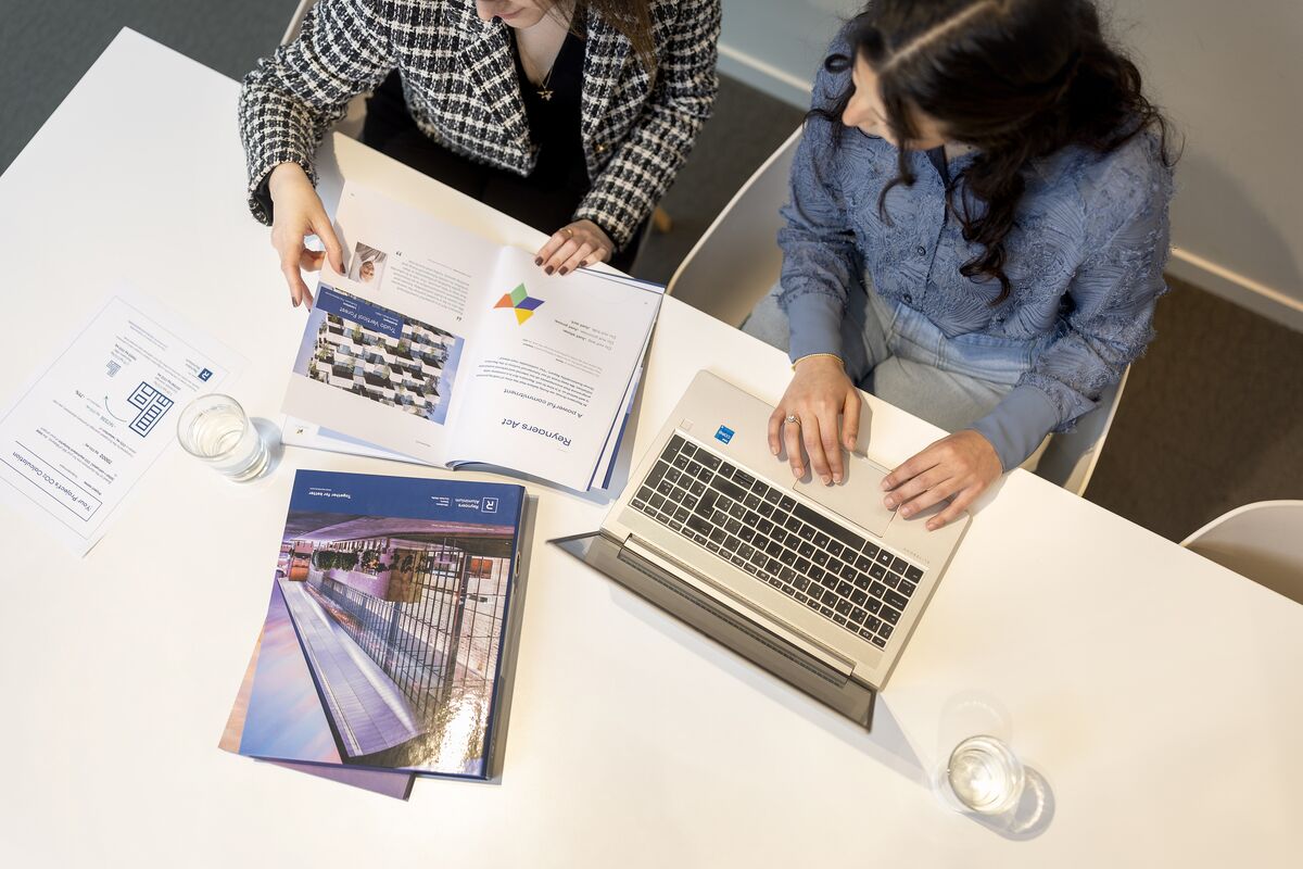 Top view of desk with papers, laptop and binders.