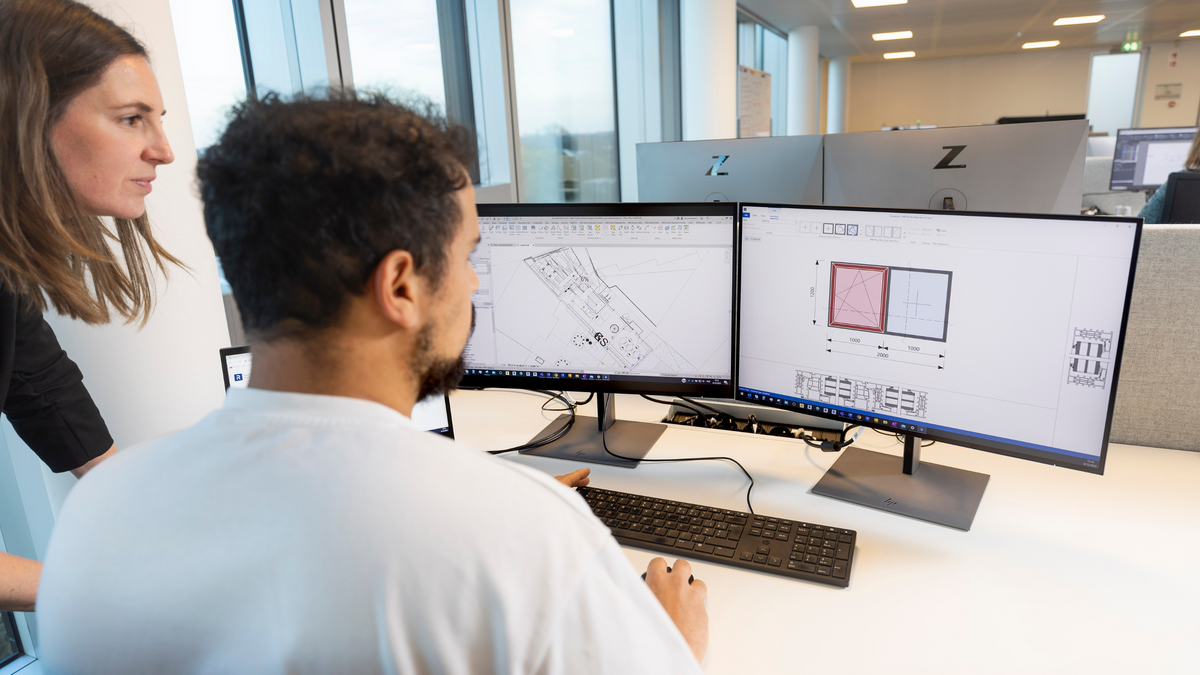People at a desk looking at a computer software on the screen