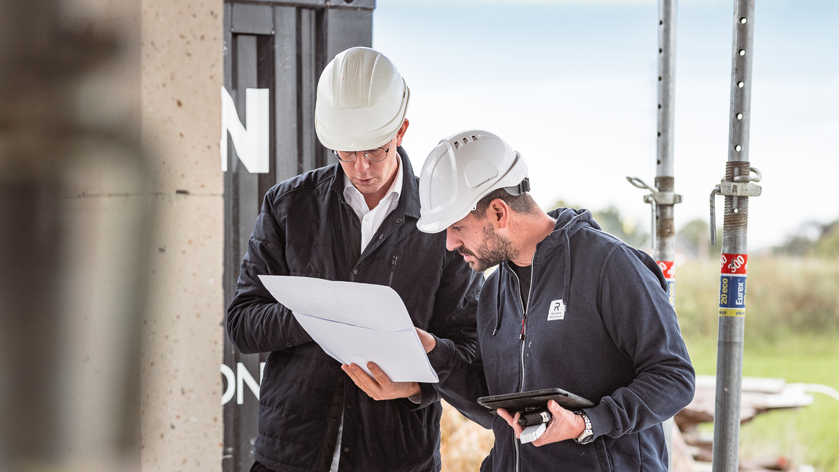 Two men on a building site looking at a piece of paper