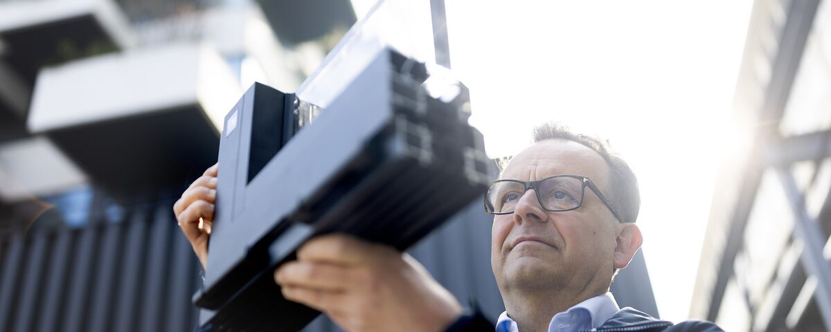 Man with glasses looking closely to aluminium corner sample.