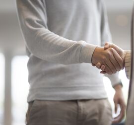 Man and woman shaking hands in office building.