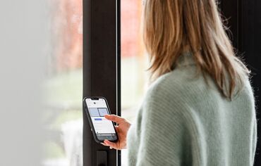 A woman looking at her phone in front of a door
