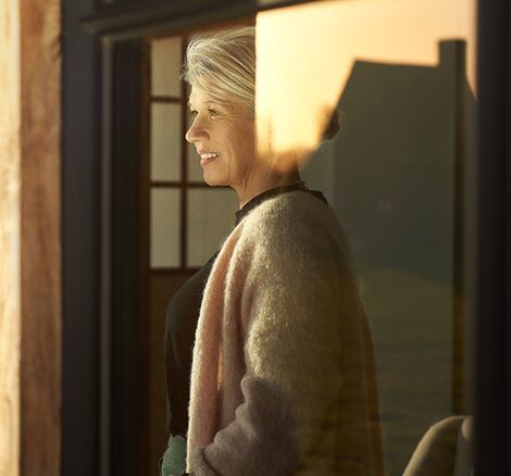 Woman looking at sunset from behind Reynaers Aluminium windows.